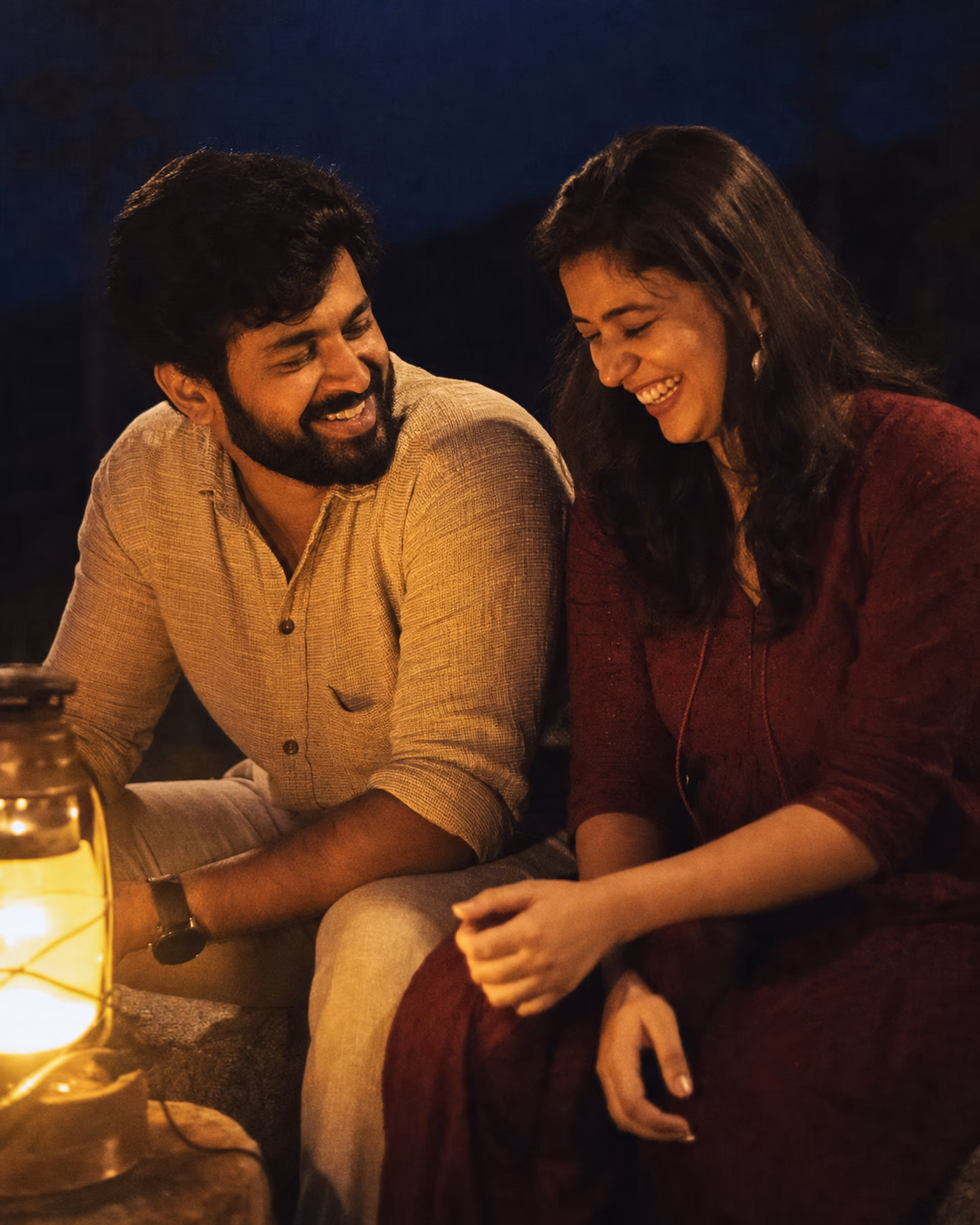Aria and Dev laughing together beside a warm lantern