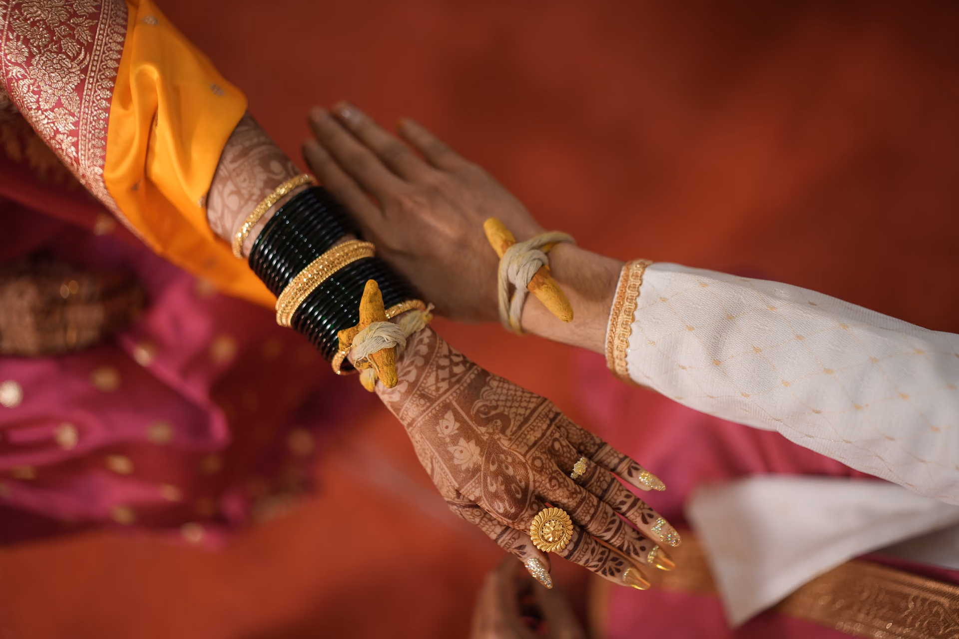 Two wrists side by side, each tied with the turmeric thread.