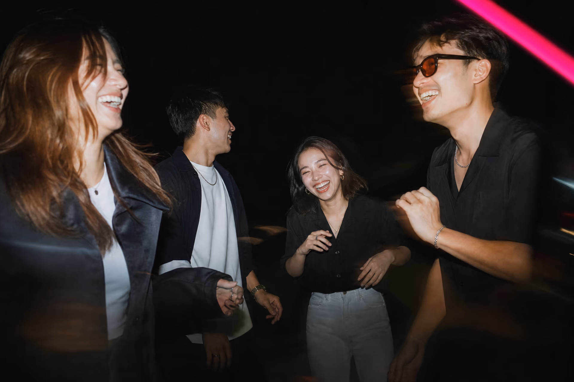Four friends laughing in motion under direct flash