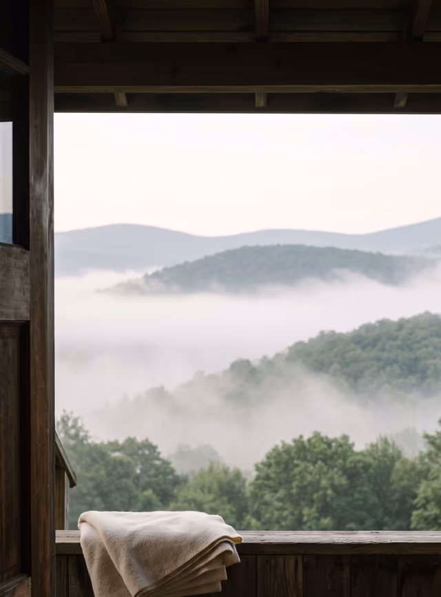 A timber lodge doorway frames mist over the wooded Catskills at first light.